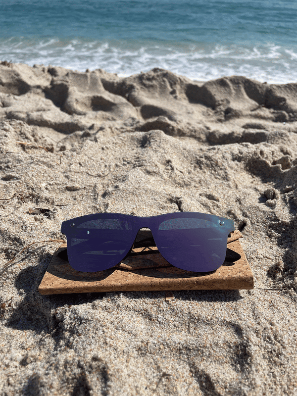 Rose gold SAARA shades on the beach with a cork foldable case it is a gif and shows the sunglasess going into the case and then sitting flat followed by fingers held up in the lens showing 1,2,3,4,5, fingers, you can see the ocean splashing in the background