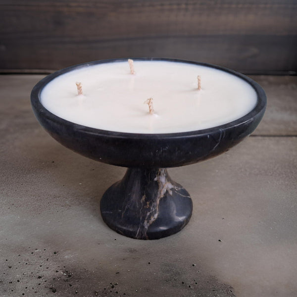 Candle in a black marble holder on a concrete surface