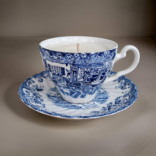 Blue and white teacup and saucer with a candle on a gray background