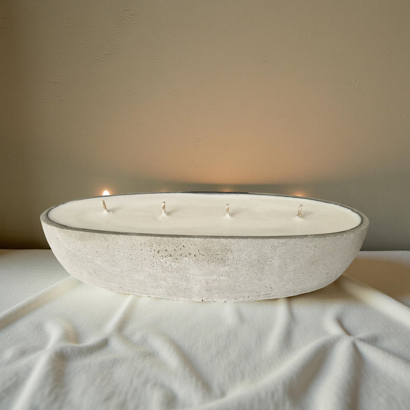 Bowl-shaped candle with multiple wicks on a textured surface