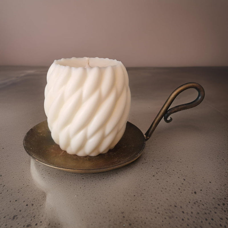 White textured candle on a metal holder with a neutral background
