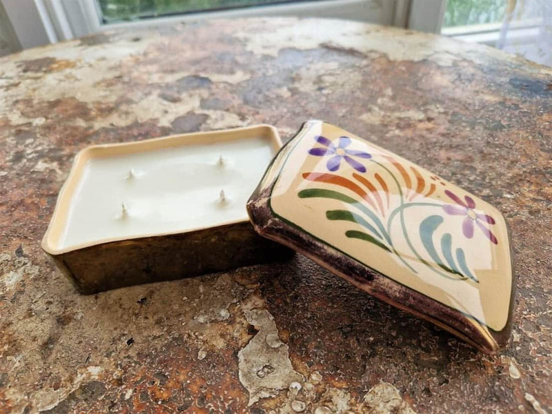 Decorative candle in a hand-painted wooden holder on a textured surface
